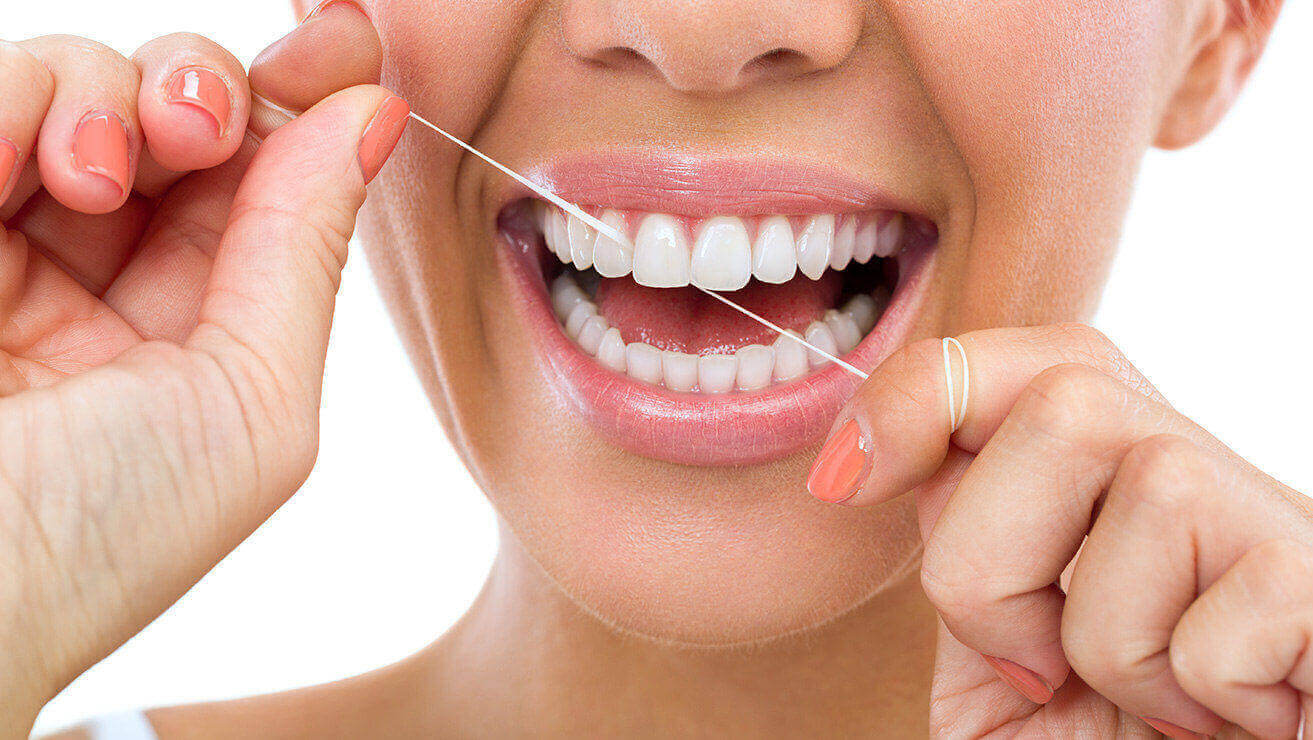 Frau verwendet Zahnseide zur Vorbeugung gegen Mundgeruch